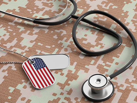 American flag identification dog tags and stethoscope on digital camouflage fabric.
