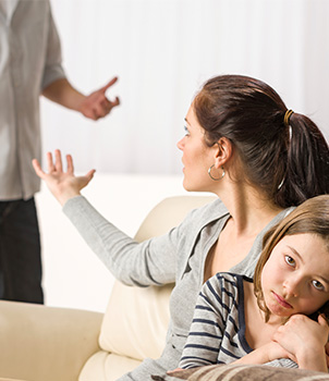 A couple argues in front of their young daughter who has anxious and frighten facial expression.