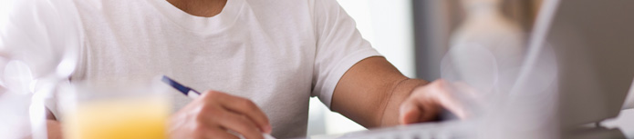 banner: a close shot of a man who makes notes in front of a computer
