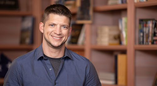A Veteran standing in front of a book shelf.