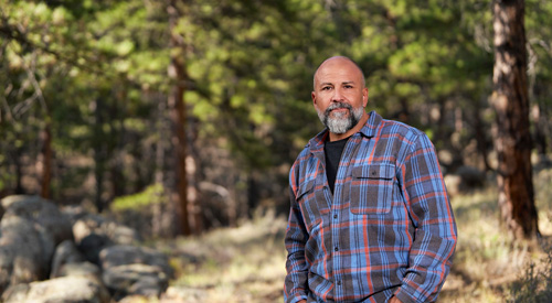 A Veteran standing in the woods.