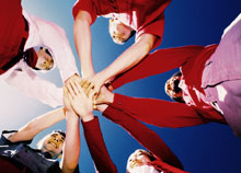 People standing in a circle with their hands stacked on top of eachother.